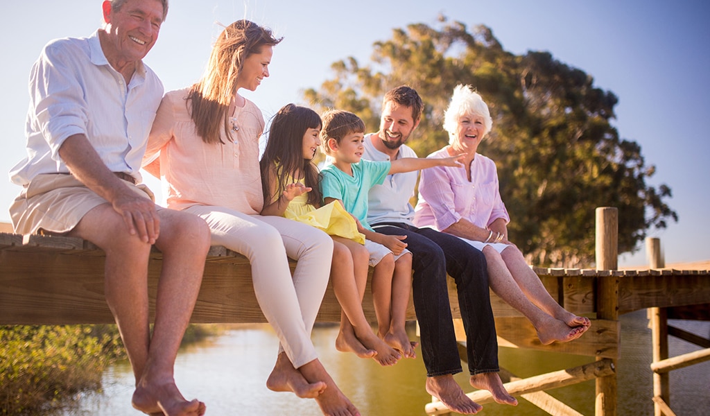 Happy multi-generational family sitting on dock